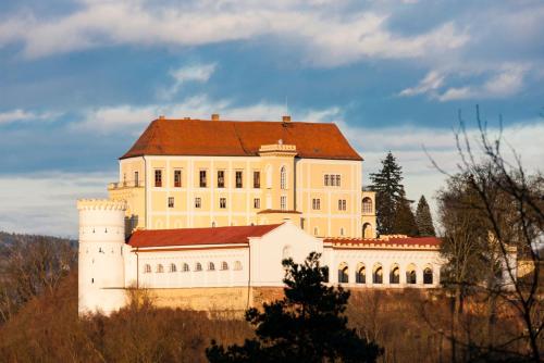 a large white building with a red roof on a hill at Chalupa u golfu Kořenec in Kořenec