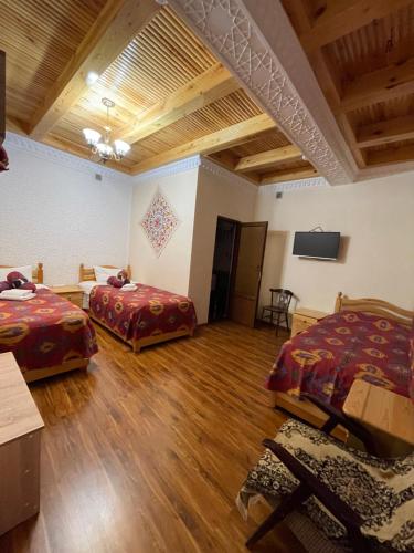 um quarto com 2 camas e uma televisão de ecrã plano em Mutara Bukhara em Bukhara