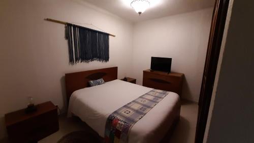 ein kleines Schlafzimmer mit einem Bett und einem TV in der Unterkunft Casinha do Rui in Sines