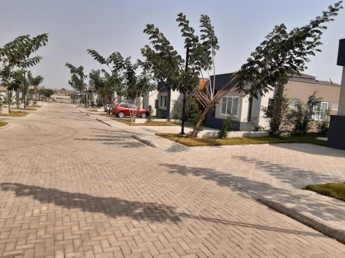 a brick road with trees and a red car on it at Accra Cozy Retreat with 2 Bedrooms in Accra