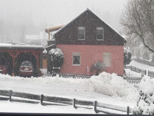 une maison recouverte de neige devant une maison dans l'établissement Privatvermietung Ina, à Buntenbock