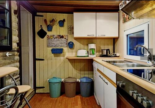 Elle comprend une petite cuisine avec des placards blancs et un évier. dans l'établissement Tiny Waldheim, à Billerbeck