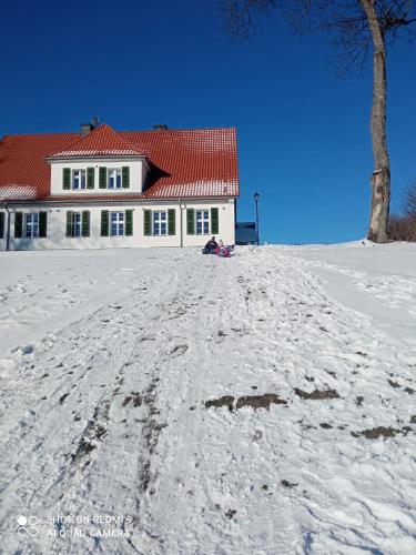 a house on top of a snow covered hill at Leśniczówka Szeroki Bór in Szeroki Bór