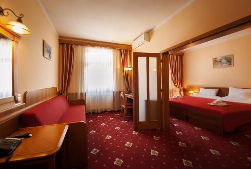 een hotelkamer met een rode bank en een bed bij Hotel Askania in Praag