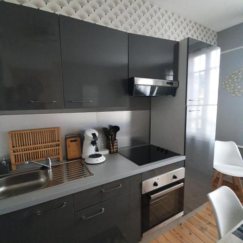 - une cuisine avec des placards noirs et un évier dans l'établissement Villa Etiennette 1, au Crotoy