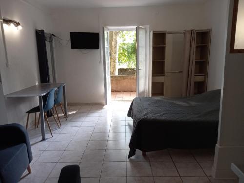 a bedroom with a bed and a table and a window at Chambres d'hôtes Domaine de Pélissols in Bédarieux