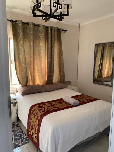 a bedroom with a bed with a chandelier above it at Sekaka Fully Furnished Apartments in Gaborone