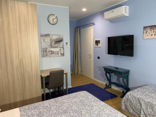 a room with two beds and a desk and a tv at Bed & Breakfast Indi Thelar in Villa Guardia