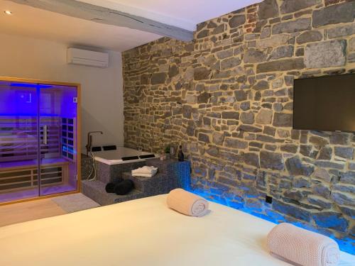 uma parede de pedra num quarto com uma cama e uma televisão em Namur à Mur em Namur