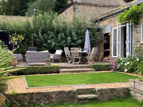 un giardino con tavolo, sedie e ombrellone di Luxury Barn Conversion at Rudding a Harrogate