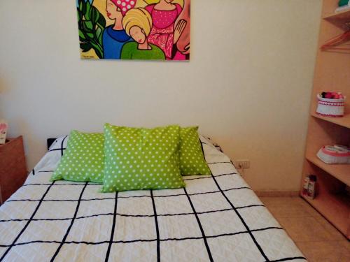 a bedroom with a bed with green and white pillows at Buenos Aires Tango Apartment near Golf in San Antonio de Padua