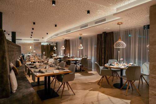 a dining room with tables and chairs and chandeliers at Resort La Ginabelle in Zermatt