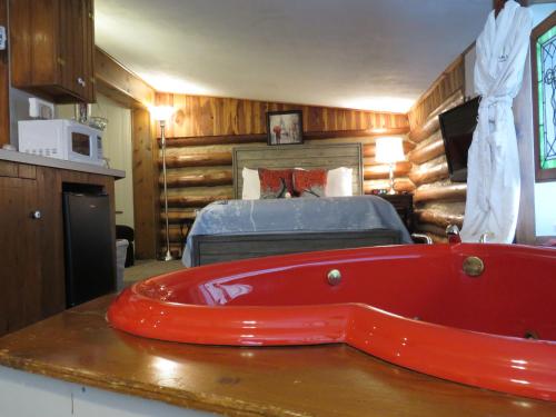 uma banheira vermelha num quarto com uma cama em Tall Pines Inn em Eureka Springs