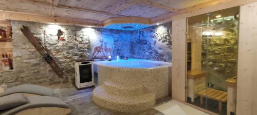 a bathroom with a tub in a stone wall at Haus Green & Spa Angelika Trentino in Lavarone