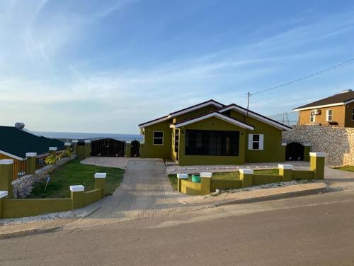 a yellow house with a fence in front of it at Villa verde Jamaica - Oceanview Getaway, Gated & Secured in Falmouth