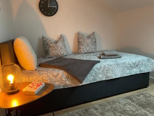 a bed with pillows and a table with a clock at Charmante Ferienwohnung 100 qm in Groß-Umstadt