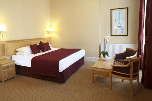 Cette chambre comprend un grand lit et une chaise. dans l'établissement Grange Buckingham Hotel, à Londres