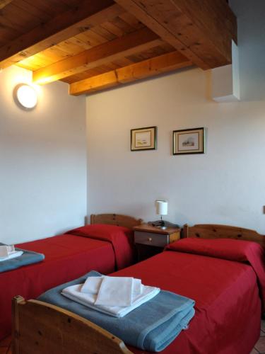two beds in a room with red sheets at Ostello Europa in San Vito al Tagliamento