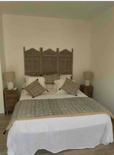 une chambre avec un grand lit blanc avec des oreillers dans l'établissement Chambre avec balcon à louer, à Bains de Guitera