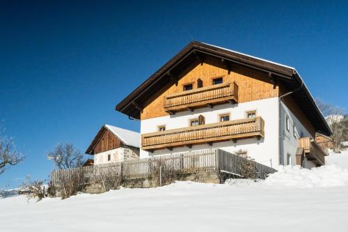uma casa com um telhado de madeira na neve em Huberhof em Terento