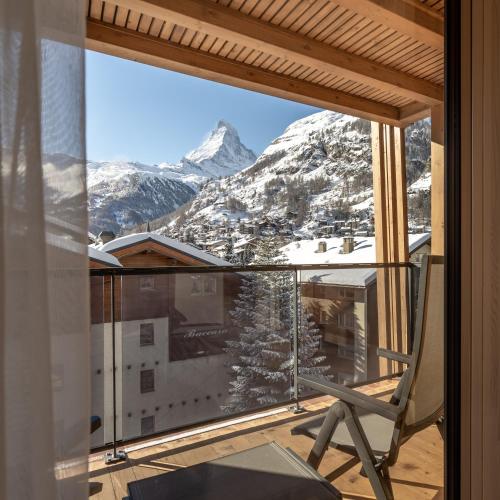 a room with a balcony with a view of a mountain at Resort La Ginabelle in Zermatt
