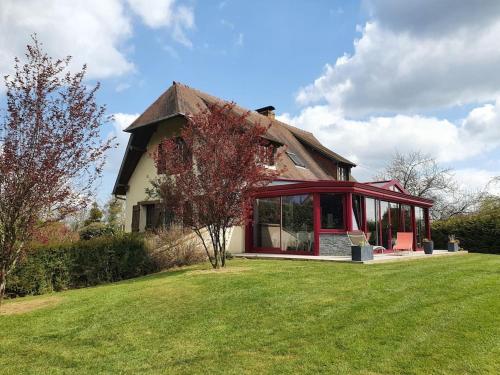 uma casa com janelas vermelhas e um quintal verde em La mare aux chevres em Reux