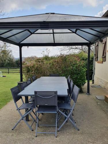 une table et des chaises sous un parasol noir dans l'établissement La mare aux chevres, à Reux