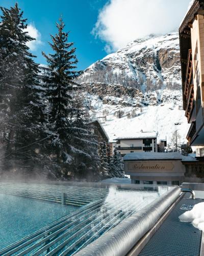 a swimming pool with snow covered mountains in the background at Resort La Ginabelle in Zermatt