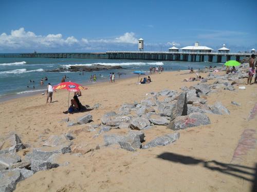 un groupe de personnes sur une plage avec une jetée dans l'établissement Suites Vila de Iracema, à Fortaleza