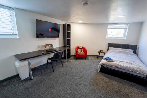 een slaapkamer met een bed en een bureau met een computer bij Spacious Comfortable studio near the university in Birmingham