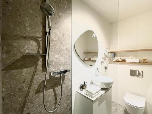 ein Bad mit einer Dusche, einem Waschbecken und einem Spiegel in der Unterkunft Studio XII in Bled