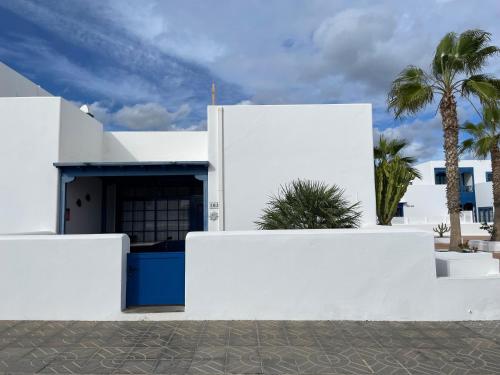 a white building with palm trees in the background at Casa Sol Azul in Puerto Calero