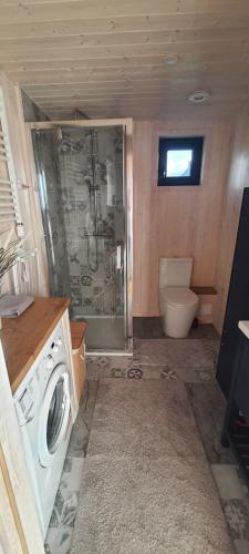 a bathroom with a shower and a washing machine at Domek mazurski całoroczny nad jeziorem z jacuzzi SPA in Pasym