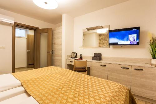 a bedroom with a bed and a desk and a tv at Sofia Place Hotel by HMG in Sofia