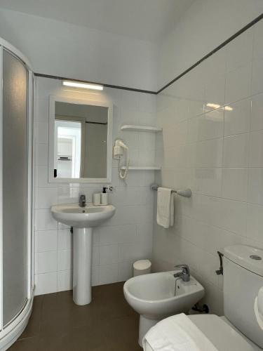 a white bathroom with a sink and a toilet at Apartamentos Mar a mar in Cala en Forcat