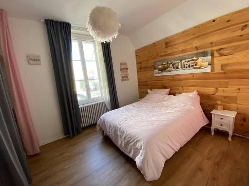 a bedroom with a white bed and a wooden wall at Maison de ville Orléans dans le Quartier Dunois avec parking privatif in Orléans