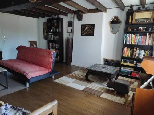 ein Wohnzimmer mit einer roten Couch und einem Bücherregal in der Unterkunft Maison Creusoise dans le village de Fontanières. in Fontanières