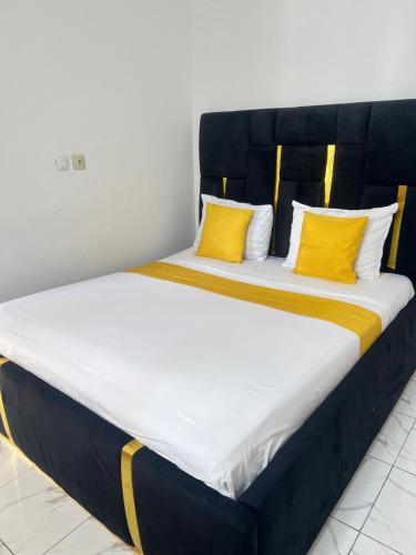 a large bed with two yellow pillows on it at Chambre Moderne (Kotto) in Douala