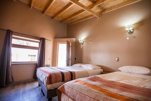 a hotel room with two beds and a window at Hotel La Cochera in San Pedro de Atacama