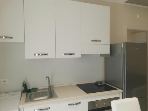 La cuisine est équipée de placards blancs et d'un réfrigérateur en acier inoxydable. dans l'établissement APPARTAMENTI SOLE-LUNA, à Francavilla al Mare