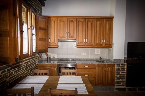 a kitchen with wooden cabinets and a wooden table at Apartamentos El Sualleiro in Santa Eulalia de Oscos