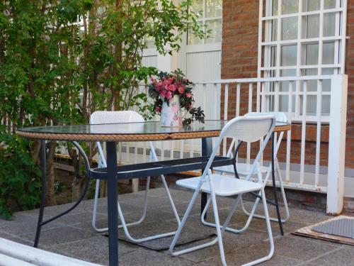 a table with two chairs and a vase of flowers at Hostería Teuly in Puerto Madryn