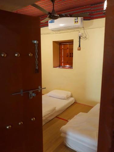 a room with two beds and a door with a window at Mahalli Balad Sayt Heritage Inn in Bilād Sayt