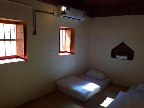 een kamer met 2 bedden en 2 ramen bij Mahalli Balad Sayt Heritage Inn in Bilād Sayt