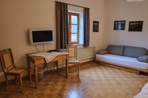 Habitación con escritorio, cama y TV. en Wirtshaus Im Schloss Fürsteneck en Fürsteneck