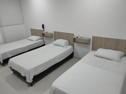 3 posti letto in una stanza con pareti bianche di HOTEL MAR DEL CARIBE a Soledad
