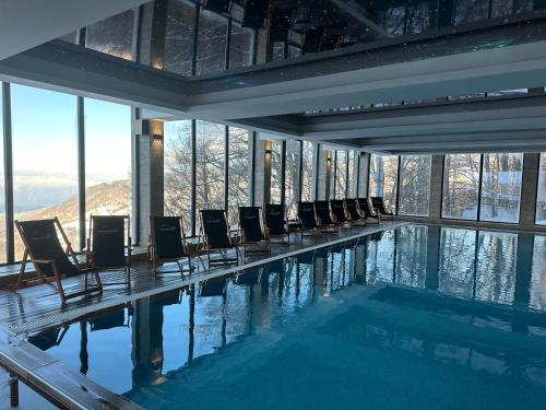 a swimming pool with chairs in a building with windows at Milmari Apartments FREE SPA & PARKING Kopaonik in Kopaonik