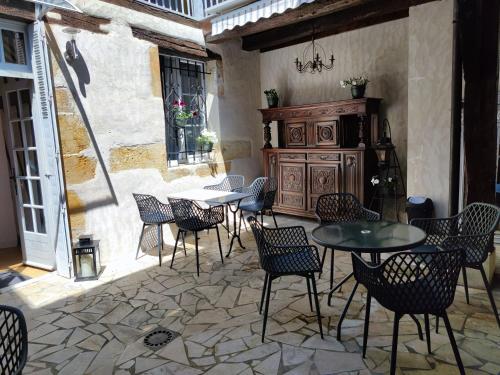 a patio with tables and chairs and a cabinet at Nogapatio - Maison d'Hôtes - BnB in Nogaro