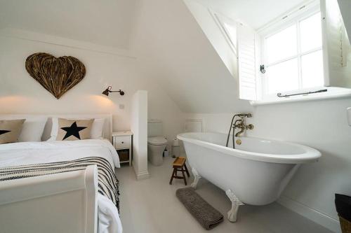 een witte badkamer met een bad naast een bed bij Fisherman's Cottage, Whitstable in Whitstable