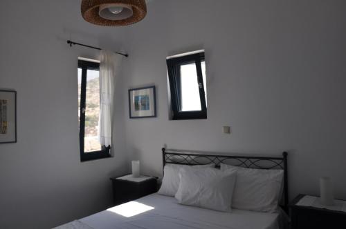 Vegera Beach House, Donoussa في دونوسا: غرفة نوم بسرير وملاءات بيضاء ونوافذ